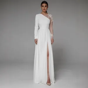 Dettaglio dell'elegante abito da sposa bianco con spacco alto e manica lunga ricamata