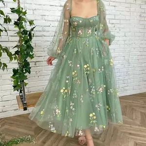 Detailed view of sage green evening dress with delicate floral embroidery and puff sleeves.