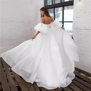Elegant off-the-shoulder white wedding dress with romantic puff sleeves and full skirt.