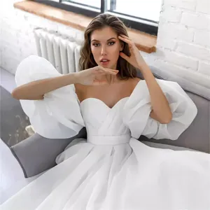 Elegant white off-the-shoulder wedding dress featuring dramatic puff sleeves and sweetheart neck