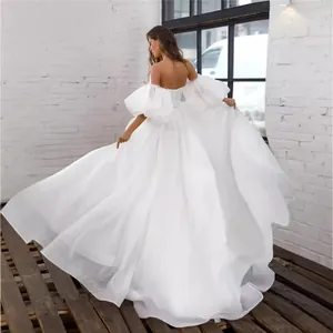 Elegant white off-the-shoulder wedding dress with voluminous puff sleeves and corset back.