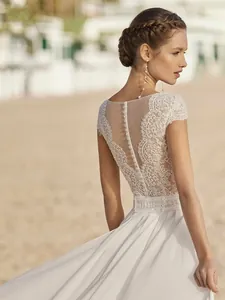 Dettaglio dell'elegante abito da sposa in pizzo bianco con schiena scoperta e bottoni fini