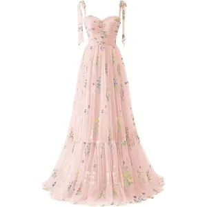 Detailed view of an elegant pink mesh evening dress with colorful floral embroidery and bow straps