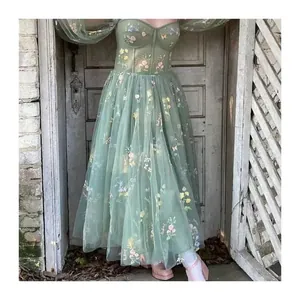 Elegant sage green tulle evening gown with colorful floral embroidery and corset bodice.