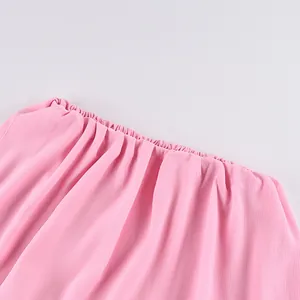 Gros plan sur la taille élastique froncée d'une jupe longue rose en mousseline fluide.