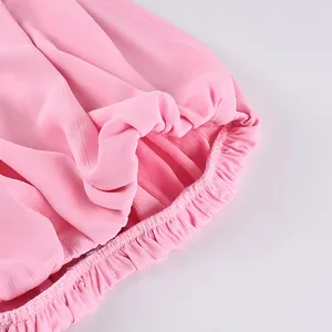 Détail en gros plan de l'ourlet élastique à volants d'une jupe longue en mousseline rose