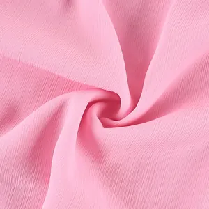 Gros plan sur un tissu en mousseline rose fluide montrant une texture plissée fine.