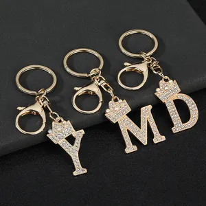 Detailed view of rhinestone-encrusted initial keychains with gold crown motifs.