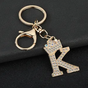 Close-up of sparkling rhinestone initial K keychain with crown on black leather background