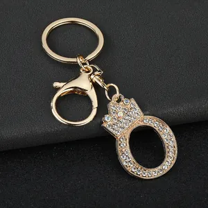 Detail showing a gold-tone letter O keychain with rhinestones and a crown charm