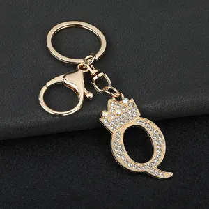 Detailed view of a gold-toned rhinestone letter Q keychain with a crown bag charm accessory