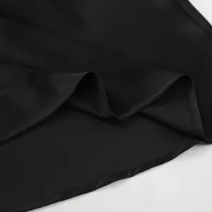 Gros plan sur l'ourlet de jupe en satin noir montrant la texture lisse et soyeuse du tissu