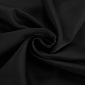Texture détaillée du tissu en soie glacée satinée noire avec un éclat élégant et drapé.