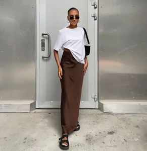 Jupe longue élégante en satin marron avec t-shirt blanc dans un décor industriel