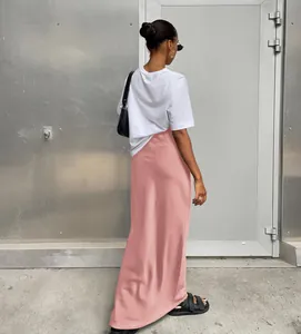 Vue arrière d'une femme portant une jupe longue en satin rose devant un mur gris