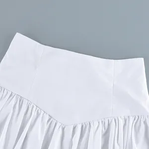 Detail view of a white cotton high-waisted skirt with elegant pleated waistline