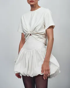 Detailed view of white twist-knot t-shirt and high-waist bubble skirt outfit