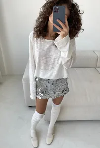Ganzkörperansicht eines silbernen Pailletten-Minirocks mit hoher Taille und weißem Oberteil.