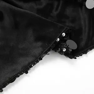 Detailaufnahme von schimmernden schwarzen Pailletten und weicher Samtstofftextur auf dem Rock
