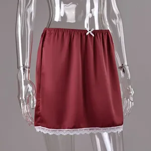 Detailed view of dark red satin mini skirt with white lace hem and bow
