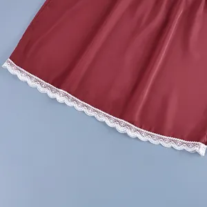 Detailed view of delicate white lace trim on the hem of a burgundy satin skirt