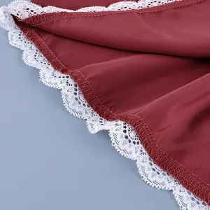 Detail macro shot of white floral lace trim on the hem of a burgundy fashion skirt