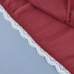 Detailed macro view of delicate white lace trim on the hem of a wine red high waist skirt