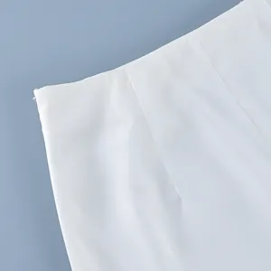 Close-up view of white high waist skirt detail with invisible side zipper and smooth fabric