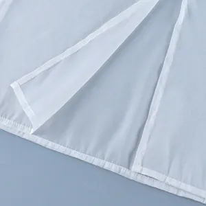 Detail of white sheer high-waisted skirt featuring a side slit and neat hemline