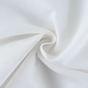 Close-up macro view of white sheer chiffon fabric with elegant soft draped swirl texture.