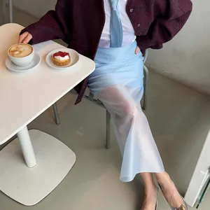 Close-up of light blue sheer high-waist midi skirt in a stylish cafe setting
