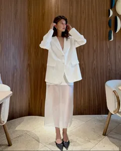 Chic white sheer high-waisted midi skirt styled with a blazer in a modern studio