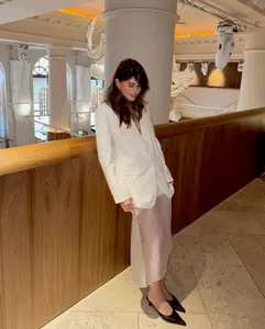Model wearing a sheer high-waisted midi skirt with a white blazer in a luxury setting.