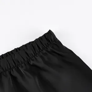 Close-up detail showing the elasticated waistband of a smooth black satin midi skirt