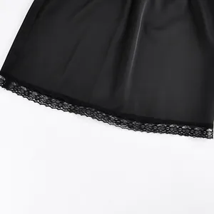 Detail macro view showing the intricate black floral lace trim on a smooth black satin skirt hemline