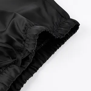 Detailed view of elasticized gathered waistband on a smooth black satin skirt