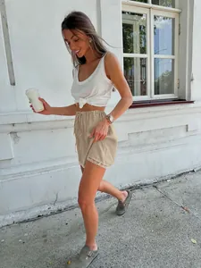 Fashionable woman wearing beige satin drawstring shorts with elegant lace trim details