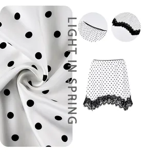 Detailed macro of white polka dot skirt with intricate black lace hem and satin finish