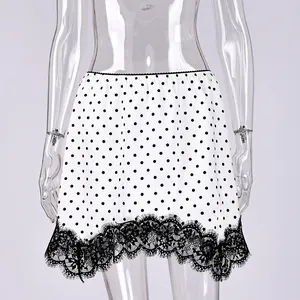Detail view of a white polka dot mini skirt with intricate black lace hem trim