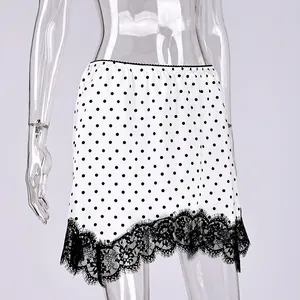 Close-up detail of white polka dot mini skirt with elegant black eyelash lace hem