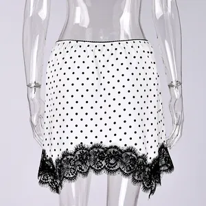 Close-up of white polka dot mini skirt with black lace hem on transparent mannequin