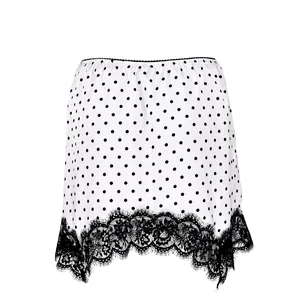 Detailed view of stylish white polka dot mini skirt featuring black eyelash lace hemline