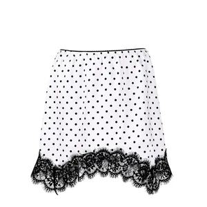 Close-up detail of the elegant white polka dot skirt featuring a delicate black lace hemline.