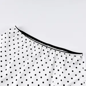 Close-up detail of the waistline with black lace trim on a white polka dot mini skirt
