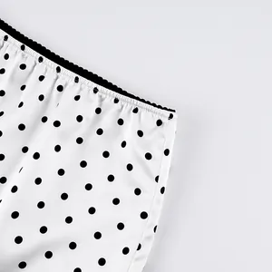 Close-up detail of a white polka dot skirt with an elegant black lace waistband