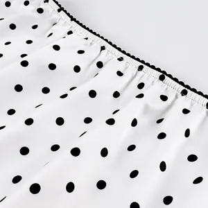 Detail of white polka dot skirt fabric with black ruffled elastic waistband.