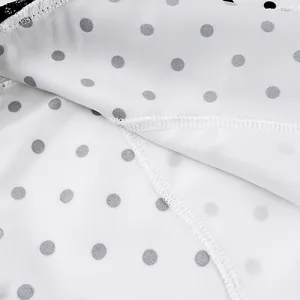 Close-up of white fabric with grey polka dots and fine stitching detail on a lace skirt