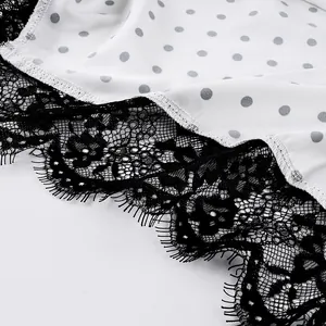 Close-up of white polka dot fabric with delicate black eyelash lace trim detail