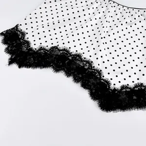 Close-up view of a stylish white polka dot skirt featuring elegant black lace trim details