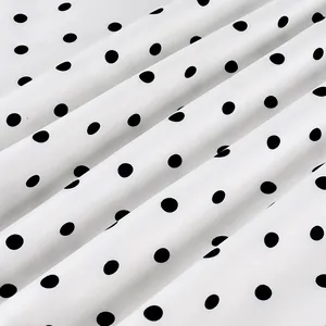 Close-up detail of white fabric with classic black polka dots showing soft folds and texture